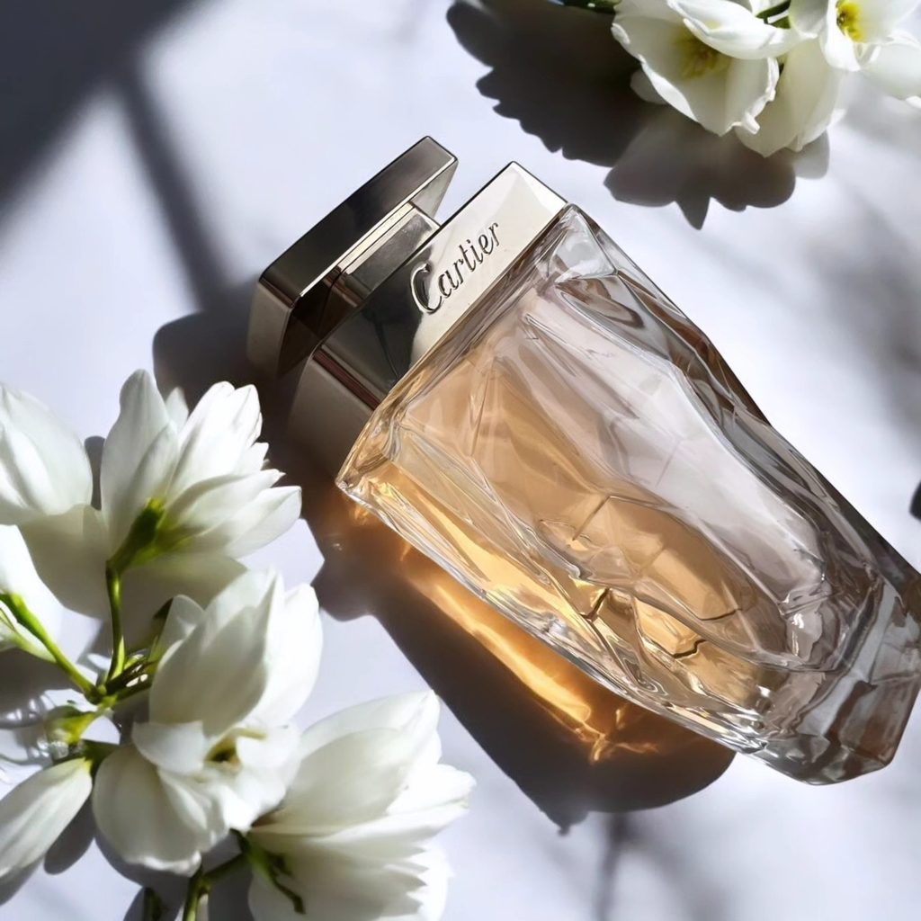 Cartier La Panthère Légère perfume bottle in soft light among white flowers